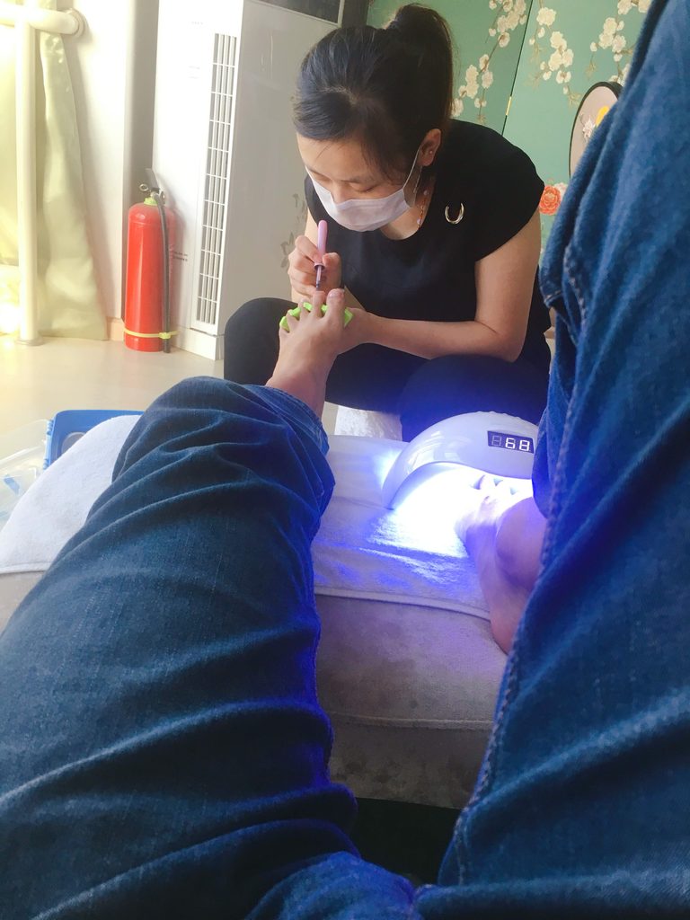 美女美甲师给男士脚趾涂甲油 / Female nail technician applying toenail polish to a man